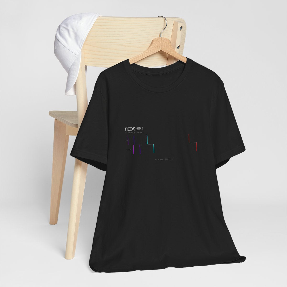 Redshift Spectra tee on a wooden hanger — hydrogen's lines, rest and redshifted, printed on black cotton.